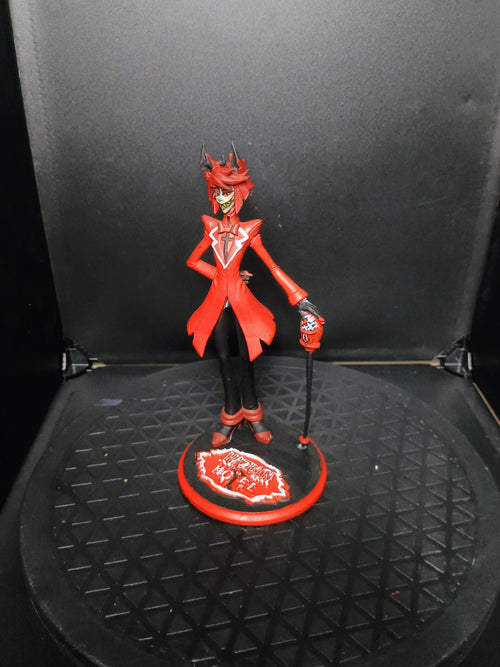 A red and black anime-style figurine of a horned character standing on a circular base, photographed against a dark backdrop.